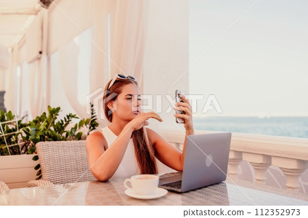 Woman coffee cafe macbook. Woman sitting at a coffee shop with mobile phone drinking coffee and looking away. Caucasian female relaxing at a cafe. 112352973