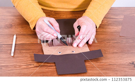Step by step. Teacher guides online class through making a paper puppet from a brown bag, creatively using a wooden surface as a workspace. Step by step. Teacher guides online class through making a paper puppet from a brown bag, creatively using a wooden surface as a workspace. 112353875