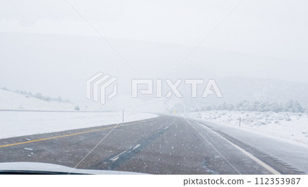 POV-Electric vehicle is captured deftly navigating the I-70 highway during a winter storm in Western Colorado. 112353987