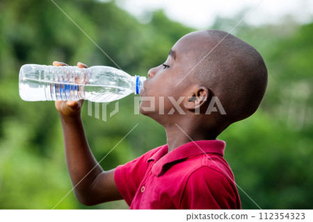 little boy drinking mineral water outdoors 112354323
