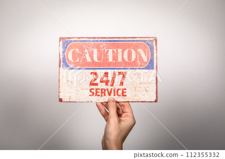 24 HRS 7 DAYS service. Metal warning sign in a woman's hand on a white background 112355332