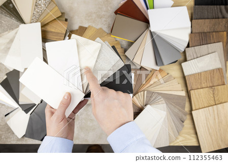 A woman looks at samples of furniture panels for furniture design. The concept of home furnishing. 112355463