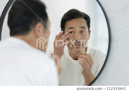 中年男子照鏡子時摀著眼角 112355641