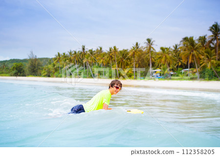 Surfer on tropical beach. Boy surfing. 112358205