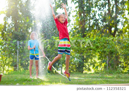 Kids play with water sprinkle hose. Summer garden 112358321
