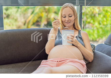 Happy pregnant young woman eating ice cream Happy pregnant young woman eating ice cream 112358399