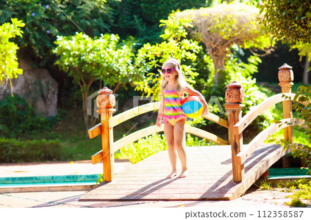 Child in swimming pool with ball. Kids swim. 112358587