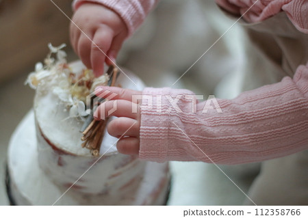 Baby's hand touching fake cake 112358766