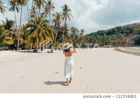 A woman in a hat enjoys the summer sun on a beautiful tropical beach 112359861