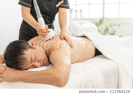 在男士美容沙龍使用空化美容機進行瘦身美容的美容師和男士（手臂和肩膀） 112360129