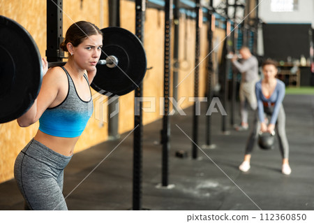 Athletic young happy woman doing barbell exercises in crossfit gym Athletic young happy woman doing barbell exercises in crossfit gym 112360850