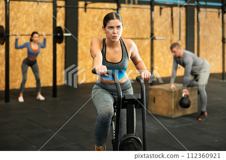 Young woman exercising on exercise bike Young woman exercising on exercise bike 112360921