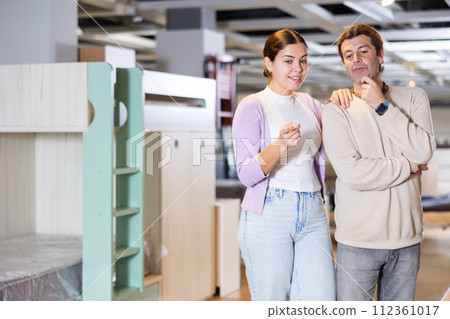 Happy man and woman choosing kids furniture in furniture showroom Happy man and woman choosing kids furniture in furniture showroom 112361017