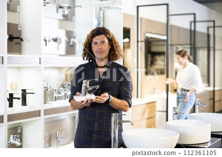 Man customer choosing faucet or spigot combination set for water supply Man customer choosing faucet or spigot combination set for water supply 112361105