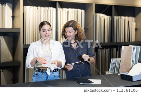 couple in large hardware store chooses ceramic tiles for repair work in kitchen and bathroom 112361106