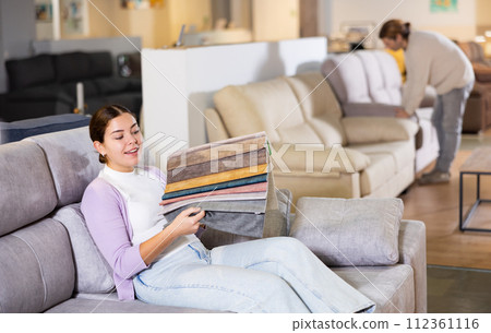 girl on the sofa infurniture store decides what fabric to choose 112361116