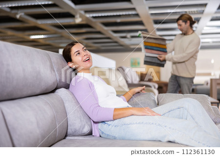 Woman deciding on buying a sofa in furniture shop 112361130