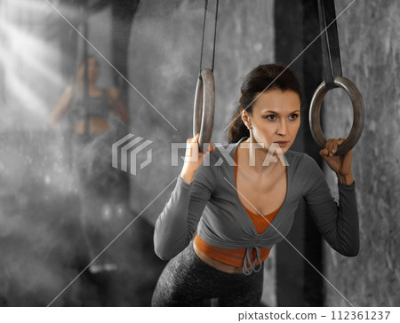 Woman performs exercises using simulator machine with rings in gym 112361237