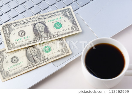 一個咖啡杯，上面有美元 (US$) 鈔票和咖啡 112362999