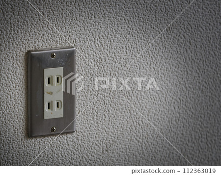 Dirty old electrical outlet on a dim wall 112363019