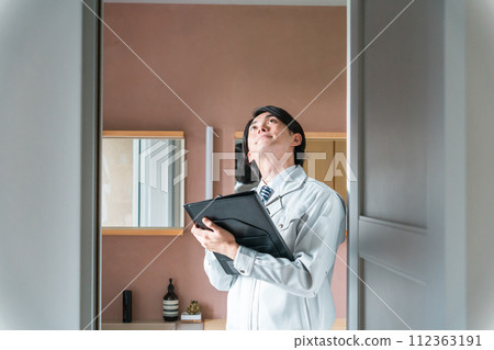 Male inspector in work clothes inspecting a house (housing inspection, property tax, administration, investigation) 112363191