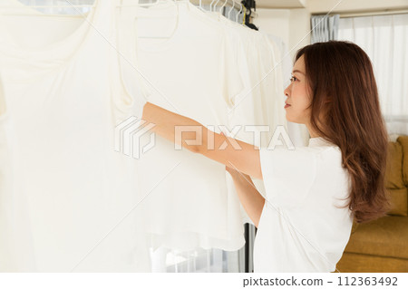 A woman hangs her laundry to dry indoors. A woman hangs her laundry to dry indoors. 112363492