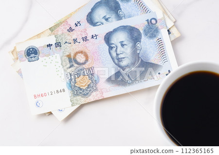 一張人民幣鈔票，上面有毛澤東的肖像和一個裝滿現煮咖啡的咖啡杯。 112365165