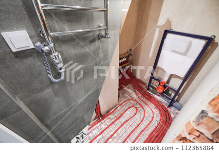 Comparison of washroom lavatory before and after renovation. Old apartment restroom with underfloor heating pipes and new renovated toilet room with electric towel dryer. 112365884