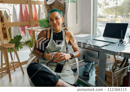 Smiling female designer sitting on background of own workshop and looks camera 112366115
