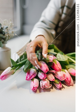 Woman's hand on pink will flowers at a table in a cafe Woman's hand on pink will flowers at a table in a cafe 112366181