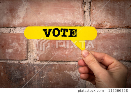 Vote. Yellow speech bubble with text on a red brick background Vote. Yellow speech bubble with text on a red brick background 112366538