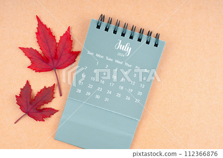 July 2024 monthly calendar and fall leaves on brown background. July 2024 monthly calendar and fall leaves on brown background. 112366876