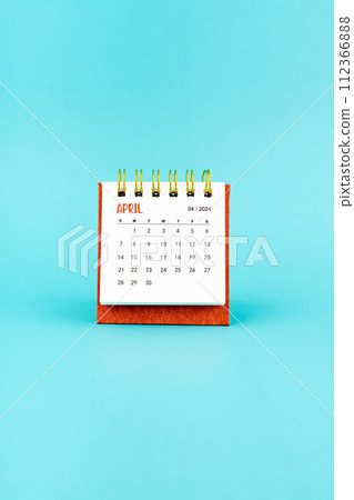 April 2024 white desk calendar on blue background. 112366888