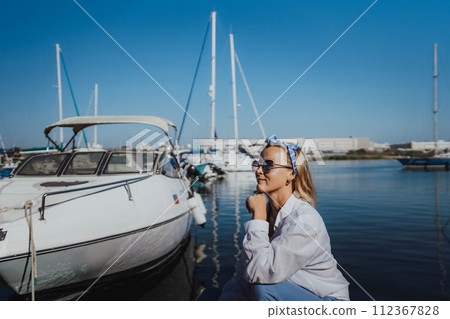 Woman in white shirt in marina , surrounded by several other boats. The marina is filled with boats of various sizes, creating a lively and picturesque atmosphere. 112367828