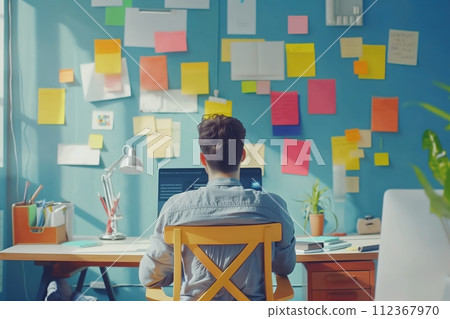 A man sits at a desk with a yellow chair and a laptop A man sits at a desk with a yellow chair and a laptop 112367970