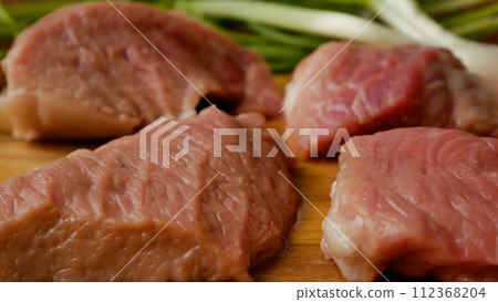 Pieces of sliced fresh pork meat on a cutting board. Meat dishes in the kitchen. 112368204