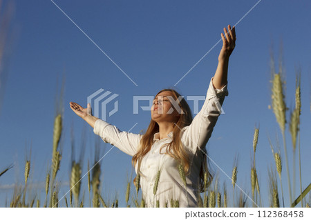 Woman in field with raised hands 112368458