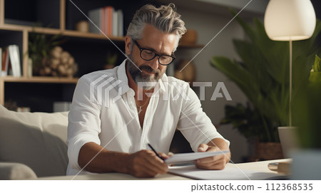 AI-generated content. A stylish adult man with a beard is sitting at a table in cozy room hold a paper and pen 112368535