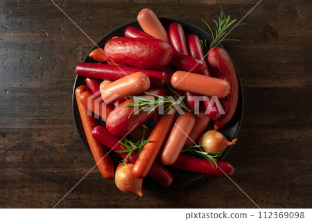 Various sausages with rosemary and onion on a old wooden table. Various sausages with rosemary and onion on a old wooden table. 112369098