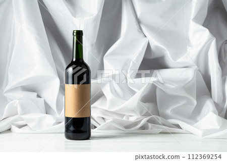 Bottle of red wine on a white wooden tfble. 112369254