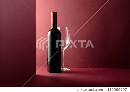 Bottle and glass of red wine on a red background. 112369307