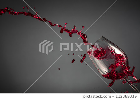 Glass and red wine splash on a dark background. Glass and red wine splash on a dark background. 112369339