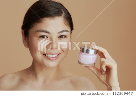 Portrait of young asian female with facial cream jar Portrait of young asian female with facial cream jar 112369447