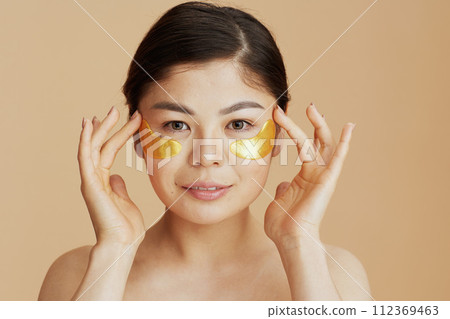 young woman with eye patches on beige background 112369463