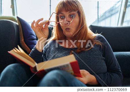 Portrait red-haired woman reading novel book 112370069