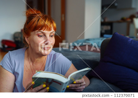 Portrait red-haired woman reading novel book 112370071