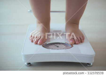 Womans feet on scale, highlighting obesity issue and healthy lifestyle importance 112370539