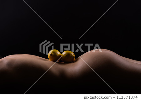Young woman with cellulite problem and lemon on dark background, closeup Young woman with cellulite problem and lemon on dark background, closeup 112371374