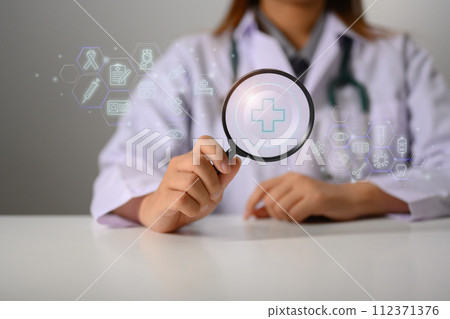 Doctor holding magnifying glass with plus sign. Health insurance and medical check up concept 112371376