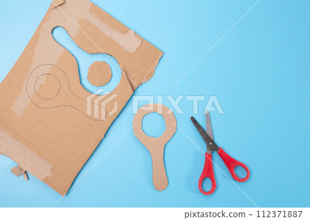 a pair of scissors sitting on top of blue surface, cut out of cardboard, magnifying glass shape, tutorial,  112371887